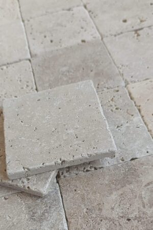 Zbliżenie na trawertyn IVORY MIX 10x10 cm, prezentujące naturalną, postarzaną fakturę kamienia.